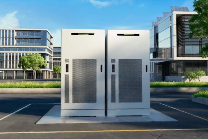 Kaksi valkoista teollisen luokan reservimarkkina-akkua asennettuna betonilaatalle modernin toimistorakennuksen edustalle