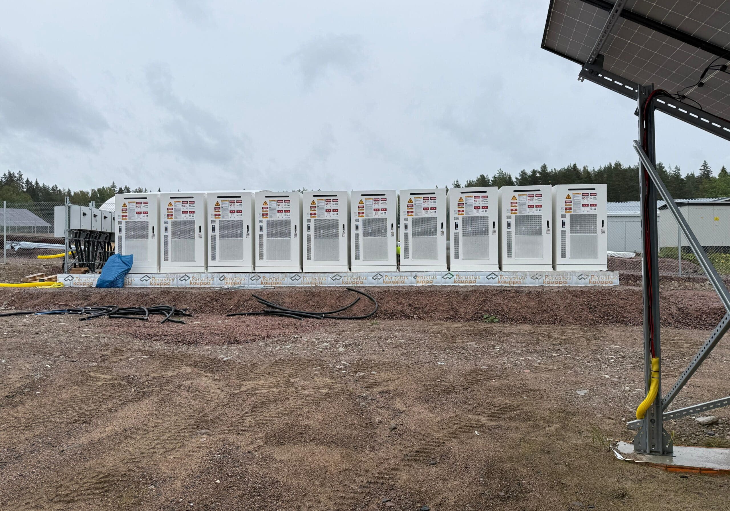 Rivi suuria energiavarastoja asennettuna ulos sorakentälle aurinkovoimalan yhteyteen.